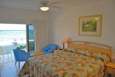 a bedroom with a large bed , a ceiling fan , and a view of the ocean at Wyndham Reef Resort Grand Cayman