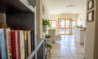 a living room with a couch , bookshelf , and potted plants , as well as a doorway leading to another room at Hotel Daniel