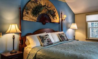 a cozy bedroom with a blue wall , a large fan hanging above the bed , and a wooden headboard above the bed at Centennial House