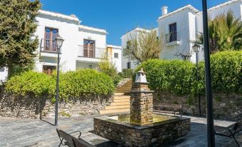 a stone fountain is in the middle of a courtyard with trees and buildings behind it at Villa Turistica de Bubion