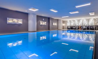 an empty indoor swimming pool with blue water , surrounded by white walls and a tv screen at Vienna Marriott Hotel