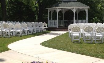 a white wedding reception setup with rows of chairs and a gazebo in the background at The Martha Washington Inn and Spa