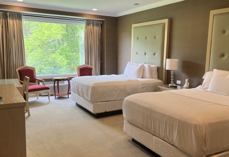 a hotel room with two beds , a chair , and a window , all arranged neatly at Rocky River Inn