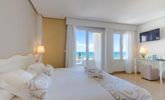 a large bed with white linens is situated in a room with a view of the ocean at Hotel Meridional