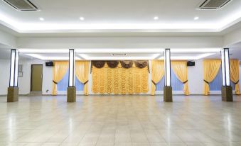 a large , empty banquet hall with multiple curtains hanging from the ceiling and wooden pillars supporting it at Hotel Sri Bernam