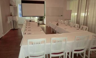 a conference room set up for a meeting , with chairs arranged in rows and a projection screen on the wall at Port Hotel