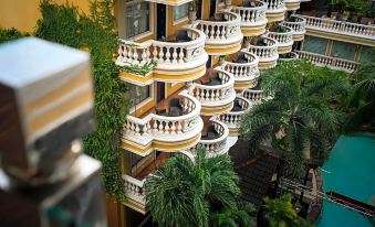 a large hotel with multiple balconies filled with green plants , creating a picturesque scene at ABC Hotel