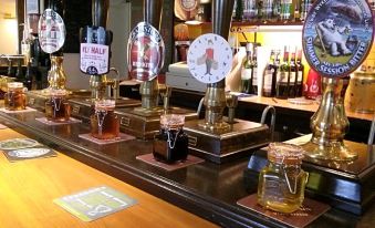 a well - stocked bar with multiple beer taps , glasses , and bottles on the counter , giving it an inviting atmosphere at The Geese and Fountain