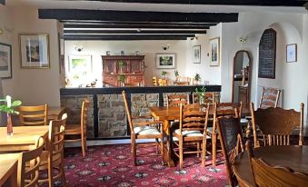 a dining room with wooden tables and chairs , along with a bar area in the background at Rose & Crown