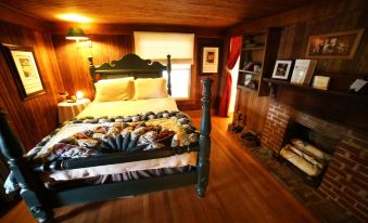 a cozy bedroom with wooden walls , a bed made of pine wood , and a fireplace at Grandview Lodge
