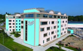 a large hotel building with a blue and pink exterior , surrounded by grass and trees at Kings Casino & Hotel