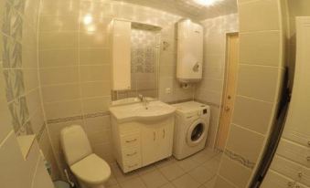 a small bathroom with beige walls , white tiles , and a toilet , as well as a washing machine in the corner at Ladya