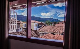 a view of a city with buildings and mountains in the background , taken from a window at Pousada Tesouro de MInas