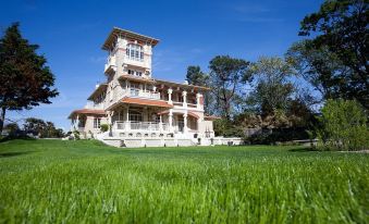 a large white house with a red roof is surrounded by green grass and trees at Villa la Tosca