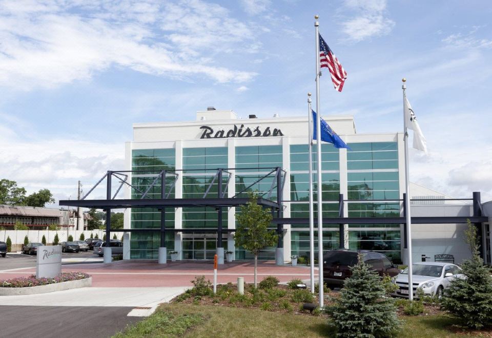 "a large building with the name "" radisson "" written on it , surrounded by trees and flags" at Delta Hotels by Marriott Milwaukee Northwest