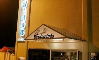 a nighttime scene of a restaurant with a large sign above the entrance , illuminating the area at Tradewinds Hotel