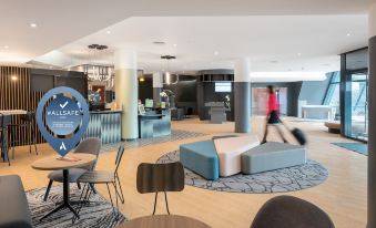 a modern hotel lobby with various seating options , including couches and chairs , as well as a coffee table at Novotel Marne-la-Vallée Noisy-Le-Grand