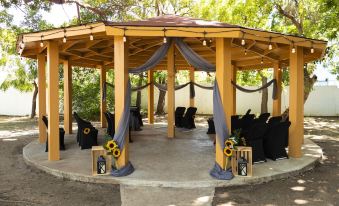 a wooden gazebo with multiple tables and chairs set up for an outdoor event , possibly a wedding at Solace by the Sea