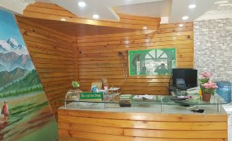 a reception area with a wooden desk and chair , as well as a television mounted on the wall at Green Leaf Resort