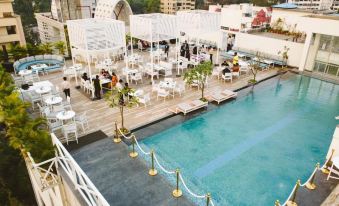 an outdoor swimming pool surrounded by a rooftop bar , with several tables and chairs set up for guests to enjoy at Hotel Centre Point