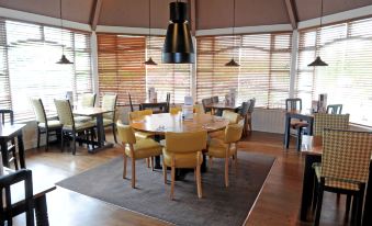 a dining room with a round wooden table surrounded by chairs , and several pendants hanging above at York North West