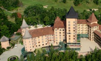 an aerial view of a large , pink building with a gray roof and two towers at The Chateau Spa & Wellness Resort