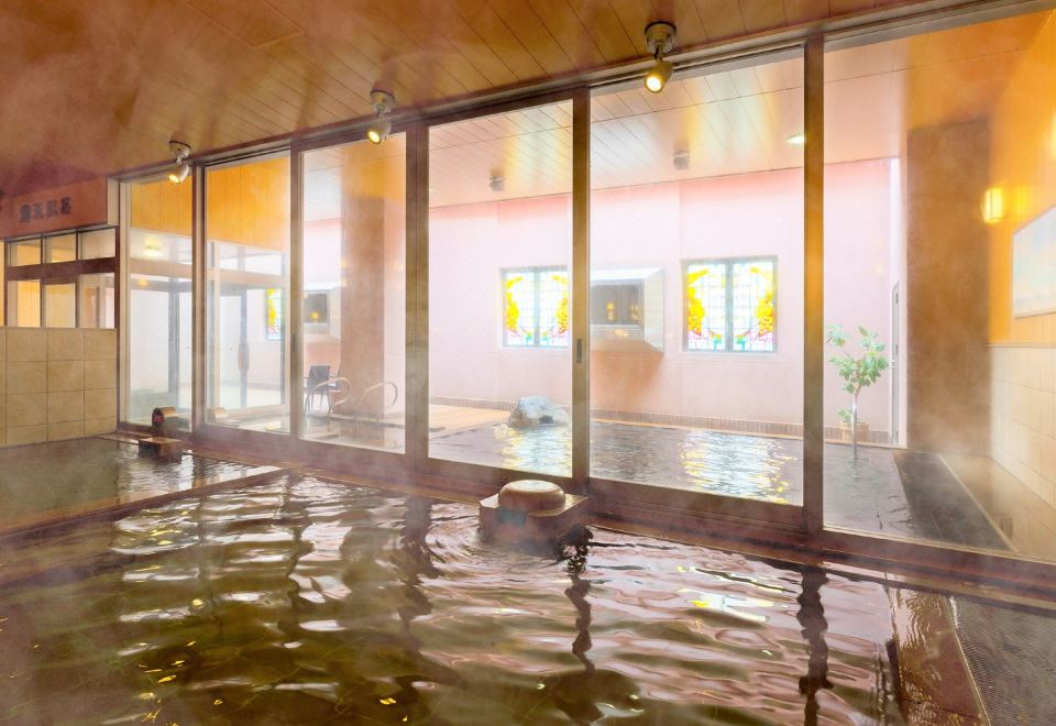 a large indoor pool with wooden walls and floor , surrounded by windows that allow natural light to enter at Hotel WBF Grande Asahikawa（Natural Hot Spring MinaPirika No Yu)