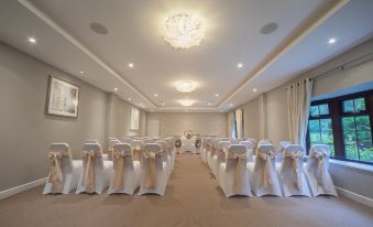 a formal event space with white chairs arranged in rows , ready for an audience to sit and listen to a speaker at The Holt Hotel