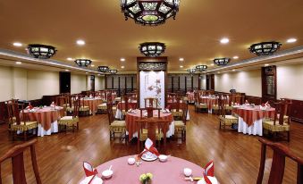 The dining room is spacious and has tables and chairs arranged for 10 people in the center at Beijing Xinqiao Hotel