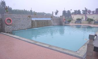 a large outdoor swimming pool surrounded by a brick wall , with people enjoying their time in the pool at Leisure Resort