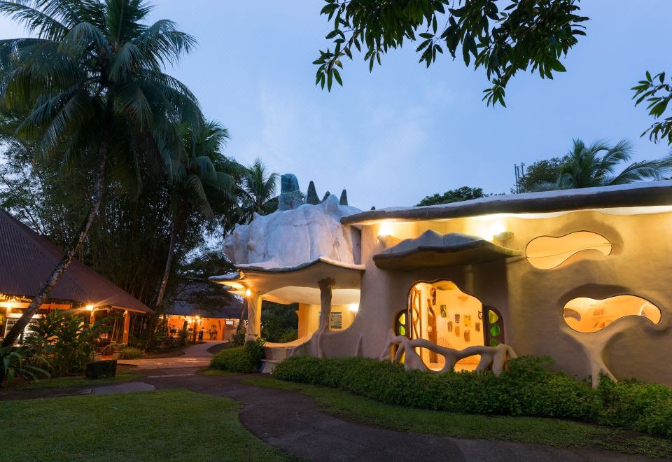 a modern , white - colored building with unique architectural design surrounded by lush greenery and a path leading to the entrance at Laguna Lodge