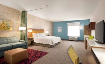 a hotel room with a bed , couch , and desk , along with blue walls and a red rug at Home2 Suites by Hilton Harrisburg North