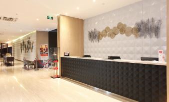 a modern office lobby with a reception desk , chairs , and a large painting on the wall at Swiss-Belinn Modern Cikande