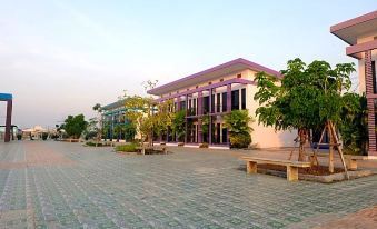 a large , modern building with purple and pink exterior is surrounded by trees and paved walkways at Menam Resort