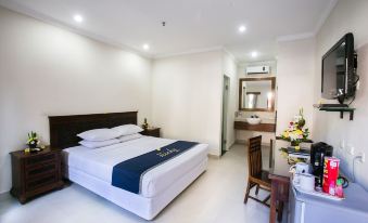 The bedroom features a double bed and a desk positioned in the center, adjacent to a large windowed door at The Niche Bali