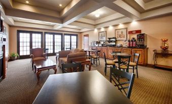 a well - lit restaurant with various dining tables and chairs , as well as a bar area at Franklin Inn and Suites