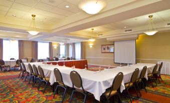 a large conference room with a long table , multiple chairs , and a projector screen , set up for a meeting or presentation at Hilton Garden Inn Wooster