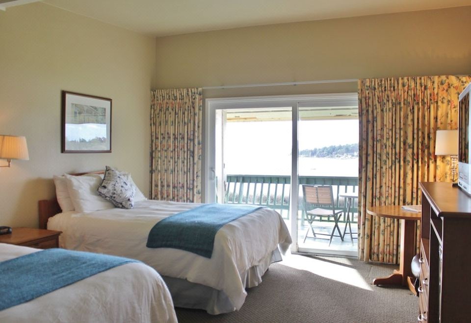 a bedroom with two beds , a sliding glass door leading to an outdoor patio , and a view of the water at Lopez Islander Resort