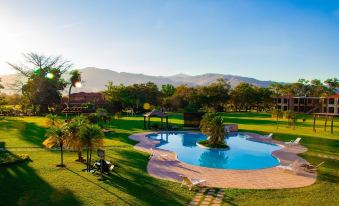 a beautiful swimming pool with clear blue water surrounded by lush greenery and mountains in the background at Grand Caporal Hotel