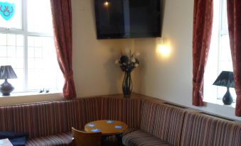 a cozy living room with a television mounted on the wall , two chairs , and a table at The Shoes