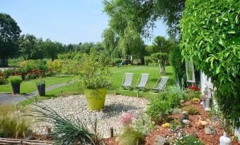 a lush green garden with a variety of plants and trees , as well as several lounge chairs at Cleome