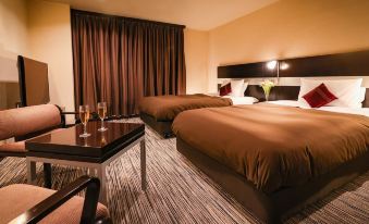 a hotel room with two beds , a dining table , and a chair , all decorated in brown colors at Fukui Hotel