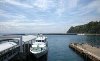 a white boat is docked at a pier in the ocean , surrounded by other boats and people at Chisun Inn Munakata