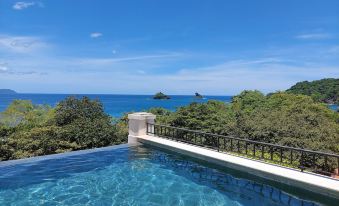 a large swimming pool with a view of the ocean and trees , under a blue sky at Santarena Hotel at Las Catalinas