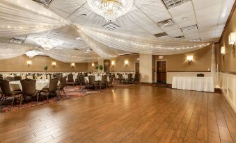 a large banquet hall with wooden floors and tables , chairs , and chandeliers hanging from the ceiling at Best Western Plus White Bear Country Inn