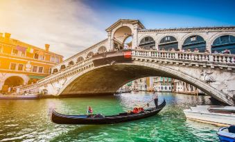 a gondola floating down a canal , with people on the bridge above and a sunny sky overhead at Best Western Titian Inn Hotel Venice Airport