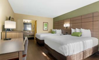 a modern hotel room with two beds , a desk , and a view of the kitchen at Best Western Downtown Stuart