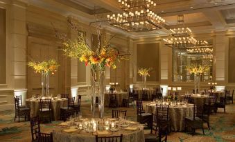 a large , well - decorated dining room with multiple tables set for a formal event , including centerpieces and chandeliers at The St. Regis Bahia Beach Resort, Puerto Rico