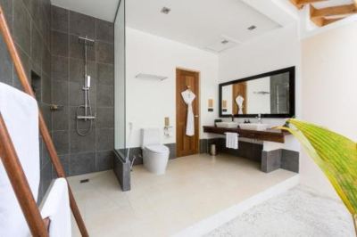 a modern bathroom with a white sink , toilet , and shower is shown next to a large mirror at Vilamendhoo Island Resort & Spa