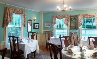 a dining room with a table set for breakfast , featuring white tablecloths and multiple chairs at Three Mountain Inn